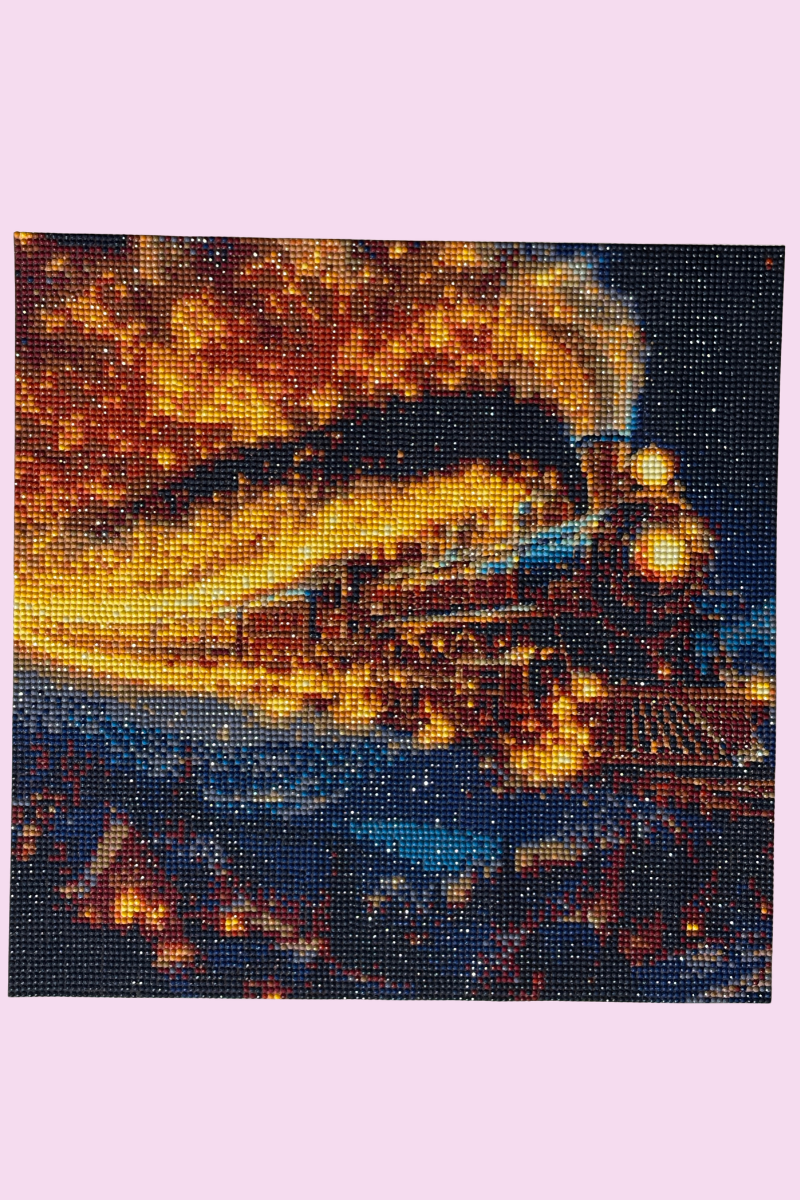 Completed diamond painting of a steam train travelling through a dramatic orange and blue landscape.